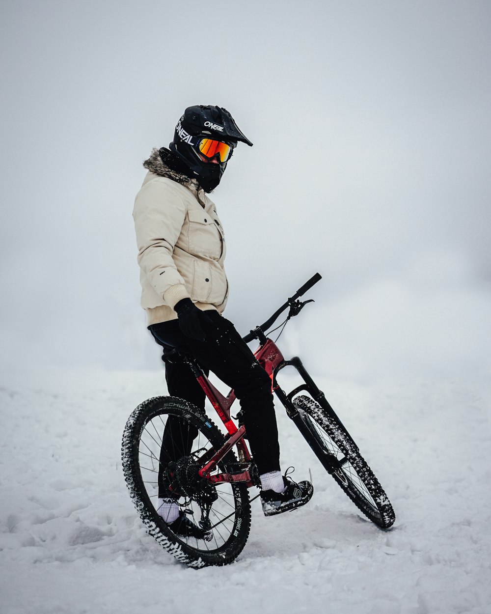 woman in beige coat riding red and black mountain bike