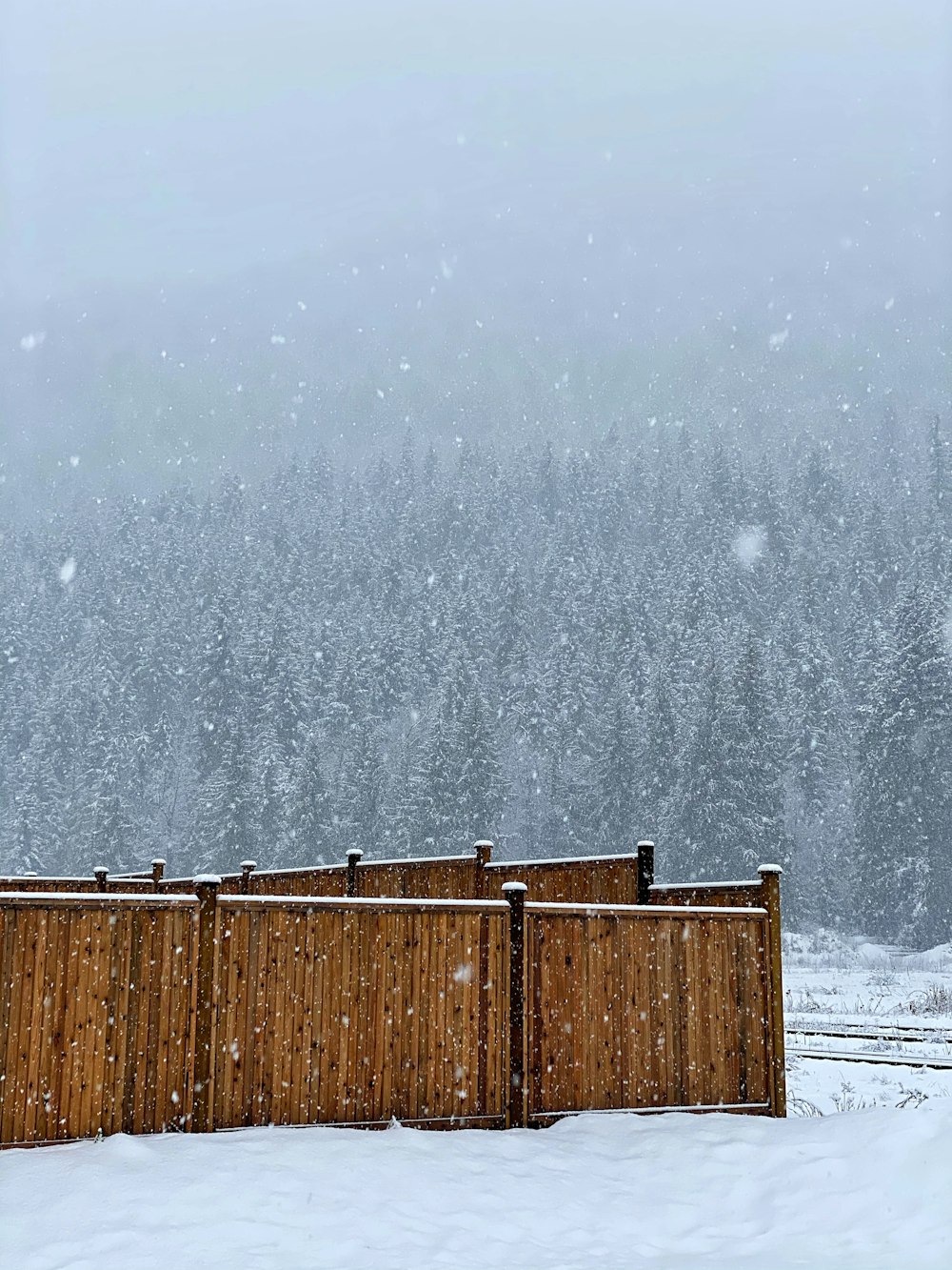 brown wooden fence on snow covered ground during daytime