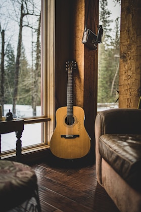 brown acoustic guitar on brown wooden chair