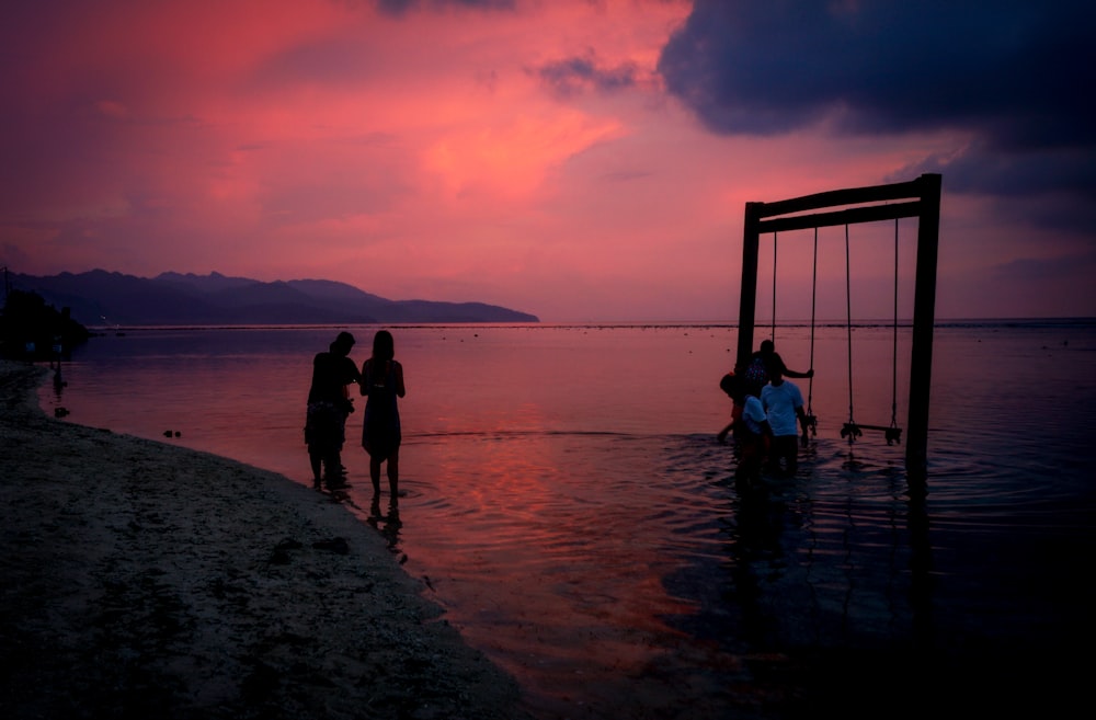 Silueta de 2 mujeres de pie en la playa durante la puesta del sol