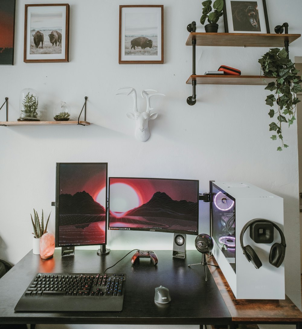 Monitor de computadora de pantalla plana negra y teclado sobre escritorio de madera negra