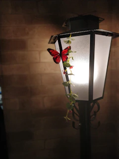 A shadowy death head hawk moth resting on a twisted wrought iron street lamp glowing faintly in violet fog.