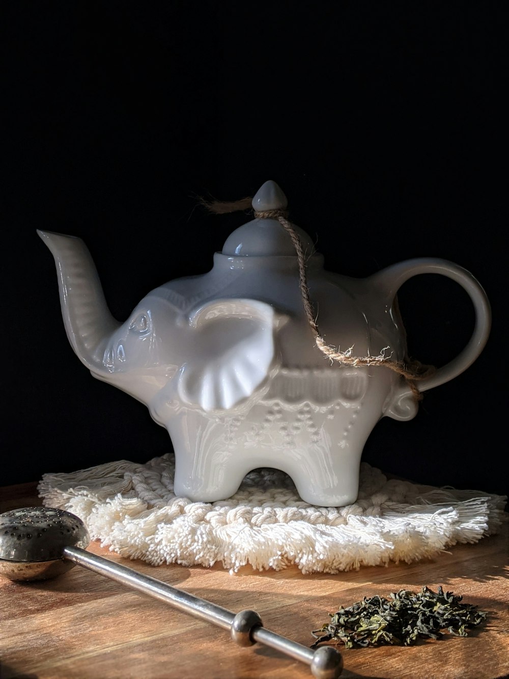 white ceramic teapot on white and brown textile