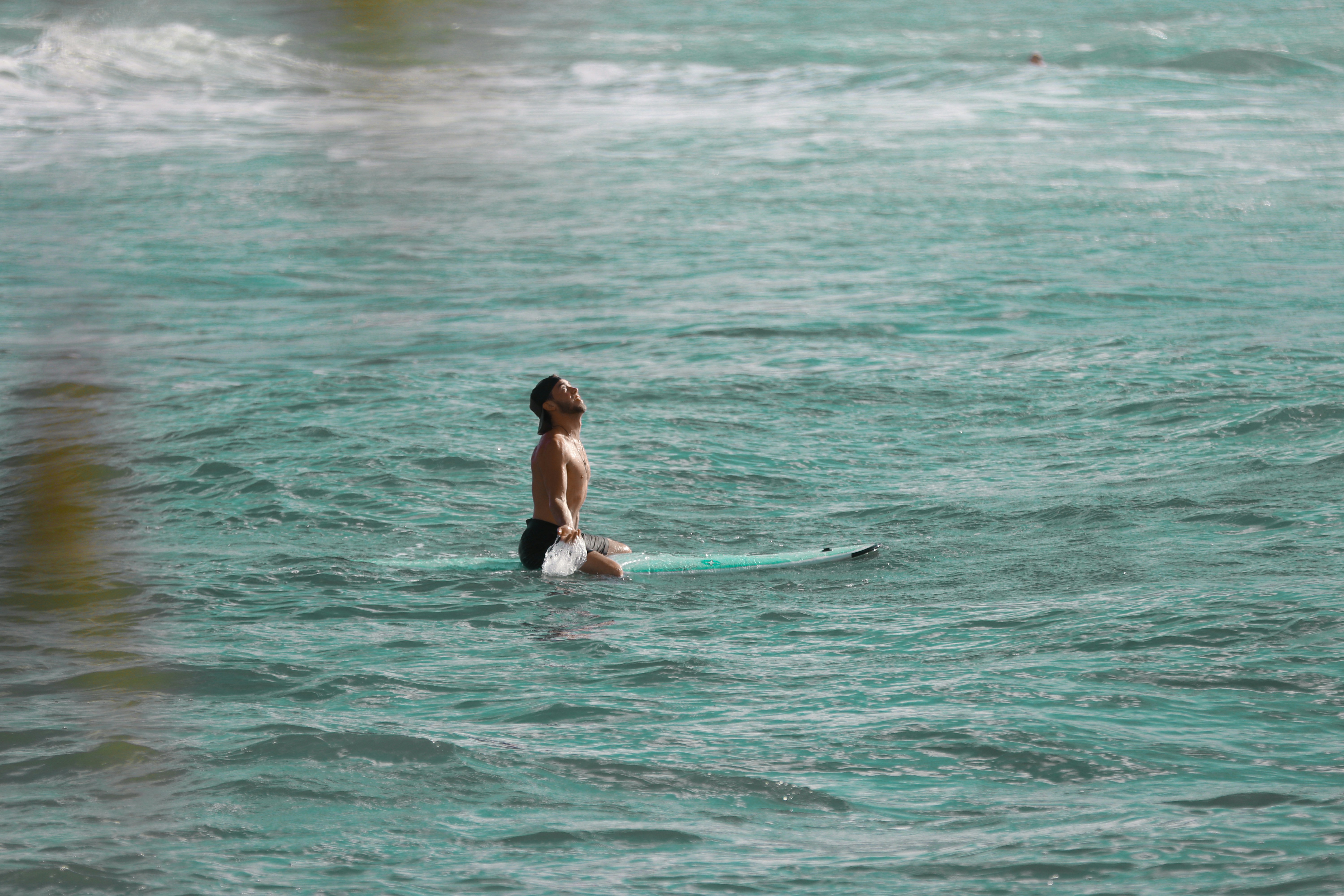 woman in black bikini surfing on sea during daytime, man looking up in the sky on surfboard 