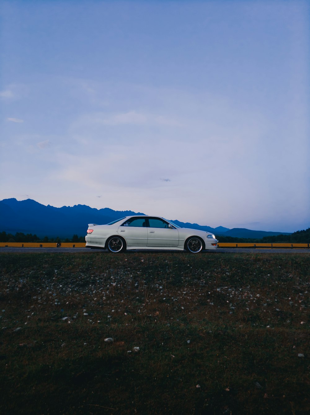 white coupe on brown dirt road during daytime