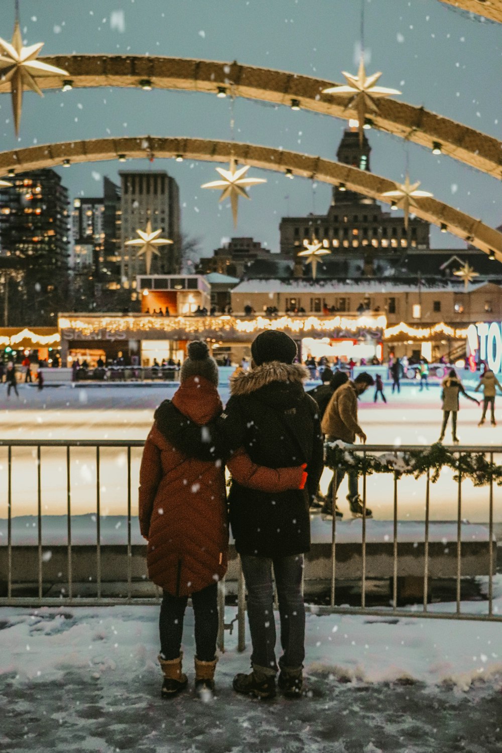 femme en manteau brun debout près de la clôture en métal blanc pendant la journée