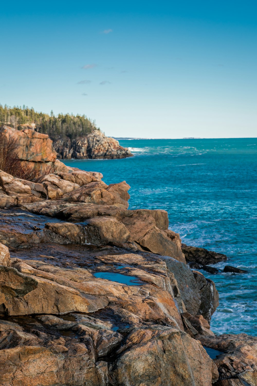 brown rocky mountain beside blue sea under blue sky during daytime