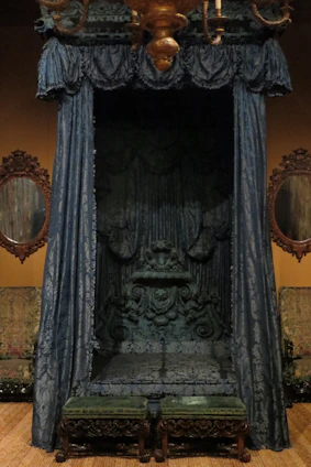 Majestic teakwood bed frame featuring royal carvings and a luxurious cream canopy