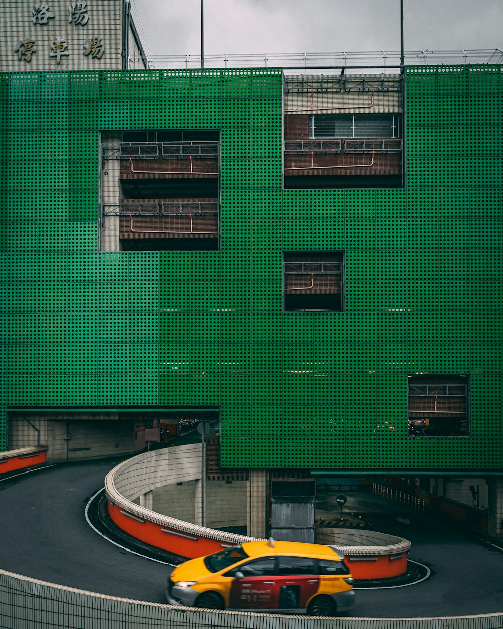 yellow car on road near green building