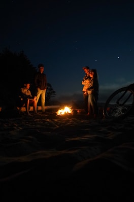 A group of bikers gathered around a campfire at dusk.