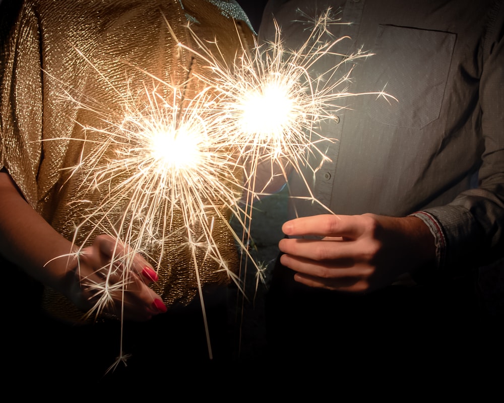 person holding lighted sparkler during nighttime