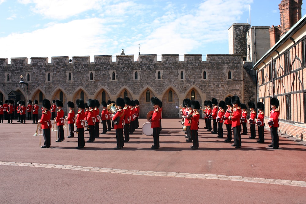 people in red and black uniform standing near brown concrete building during daytime