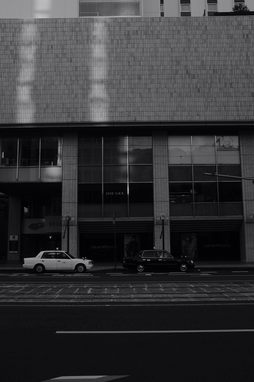 grayscale photo of cars parked beside building