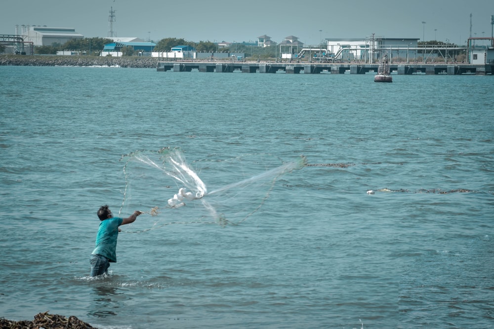 man in blue shirt and blue denim shorts standing on water during daytime