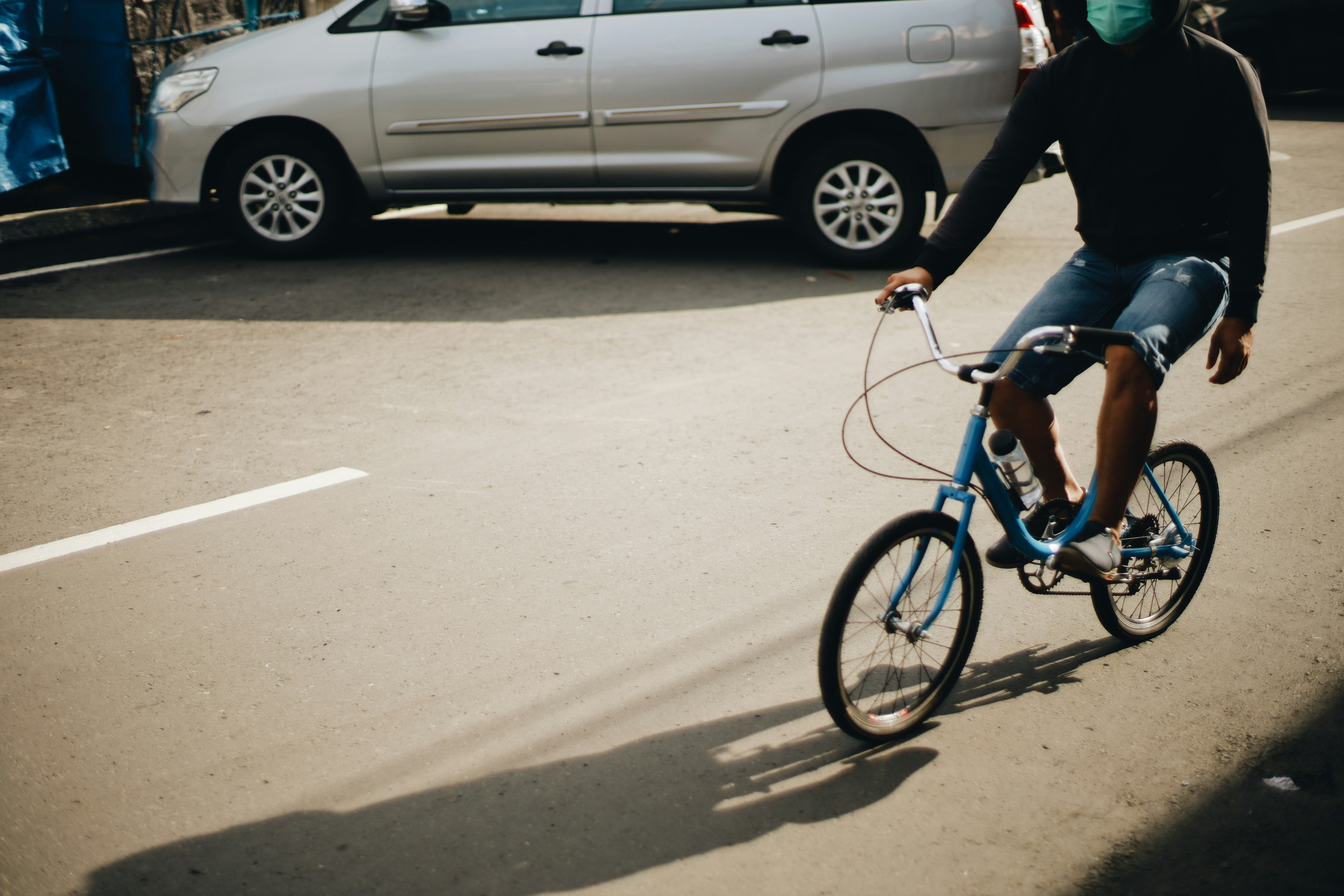 man in black jacket riding on blue bicycle during daytime