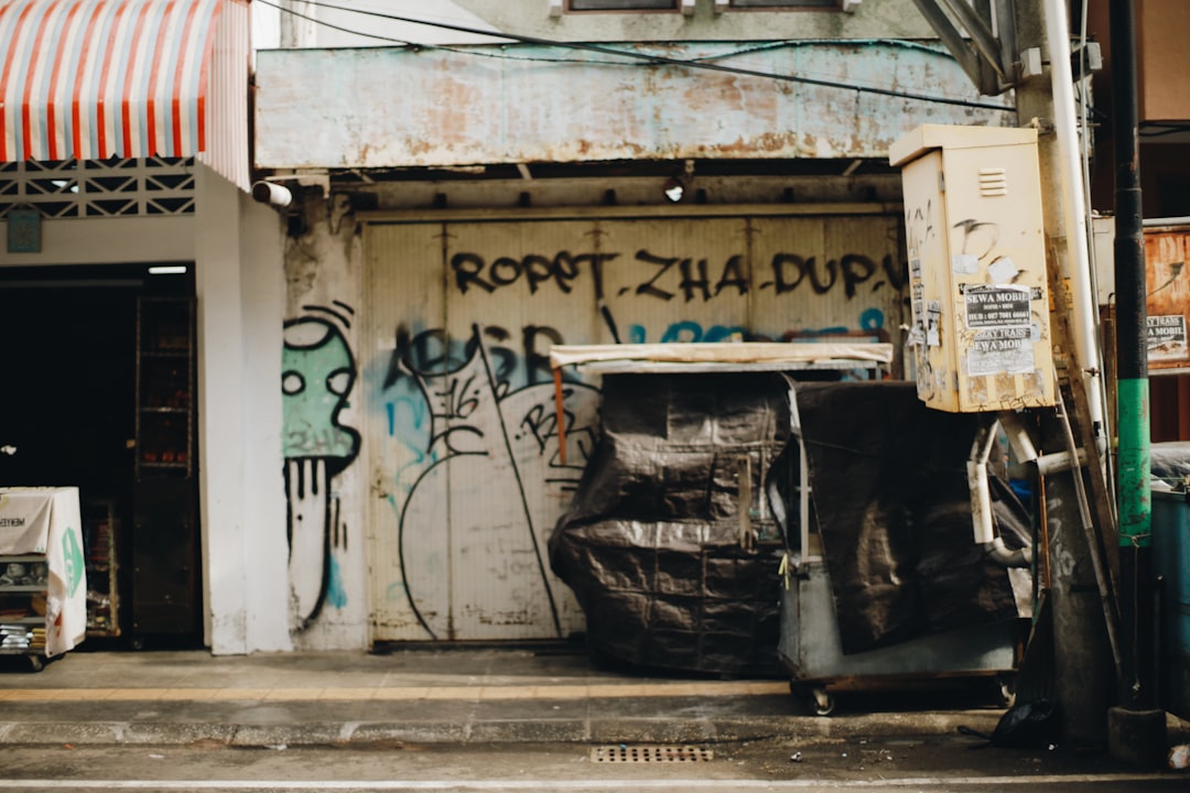 black trash bin beside white wall