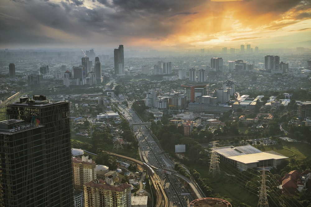 Edifici della città sotto il cielo nuvoloso arancione e grigio durante il tramonto