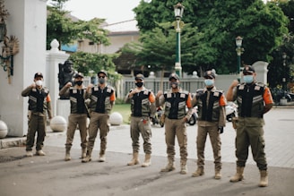 group of men in black and white uniform standing on gray asphalt road during daytime