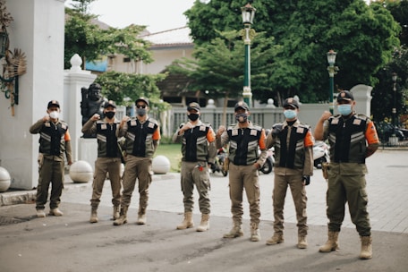 group of men in black and white uniform standing on gray asphalt road during daytime