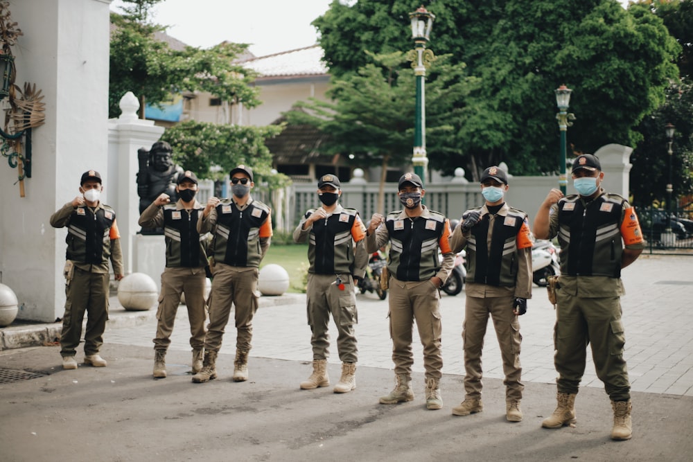 group of men in black and white uniform standing on gray asphalt road during daytime