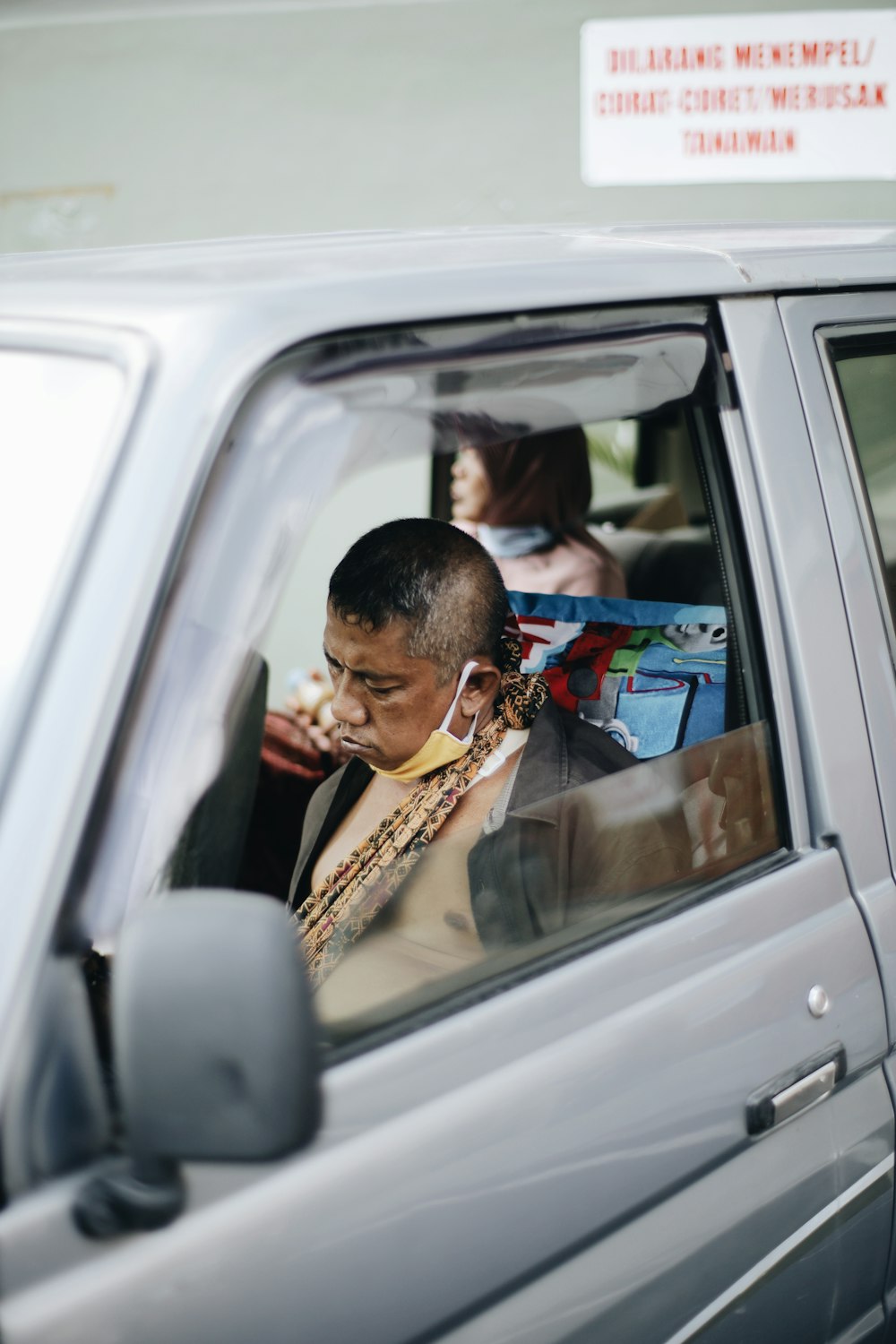 man in yellow and black shirt sitting inside car during daytime