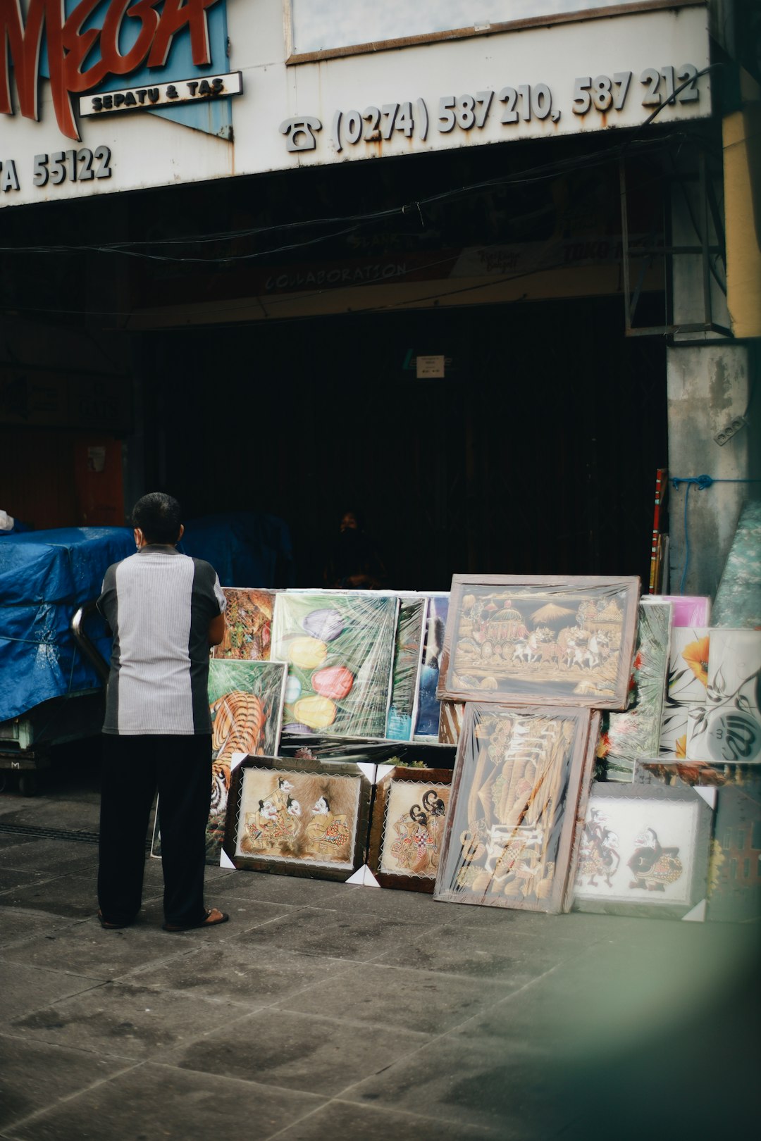 man in blue dress shirt standing beside painting