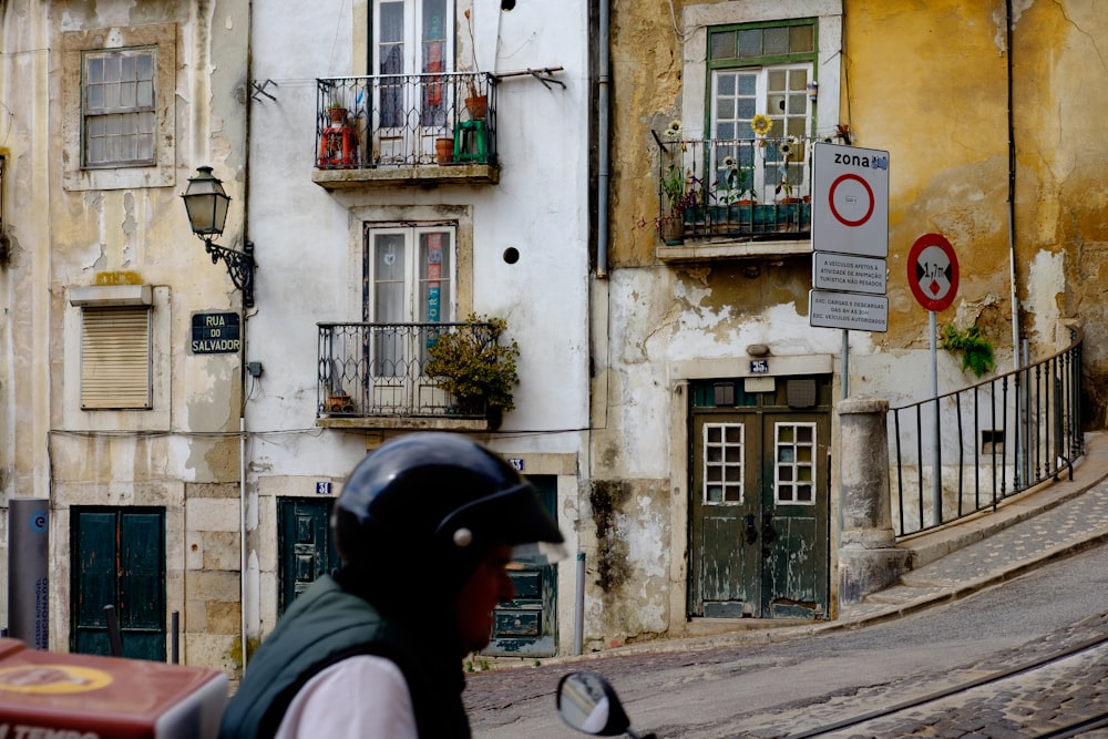 man in black helmet and pink jacket standing near white concrete building during daytime