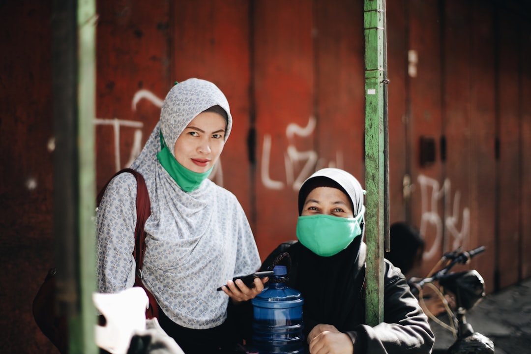 woman in gray long sleeve shirt and green hijab holding blue plastic water jug