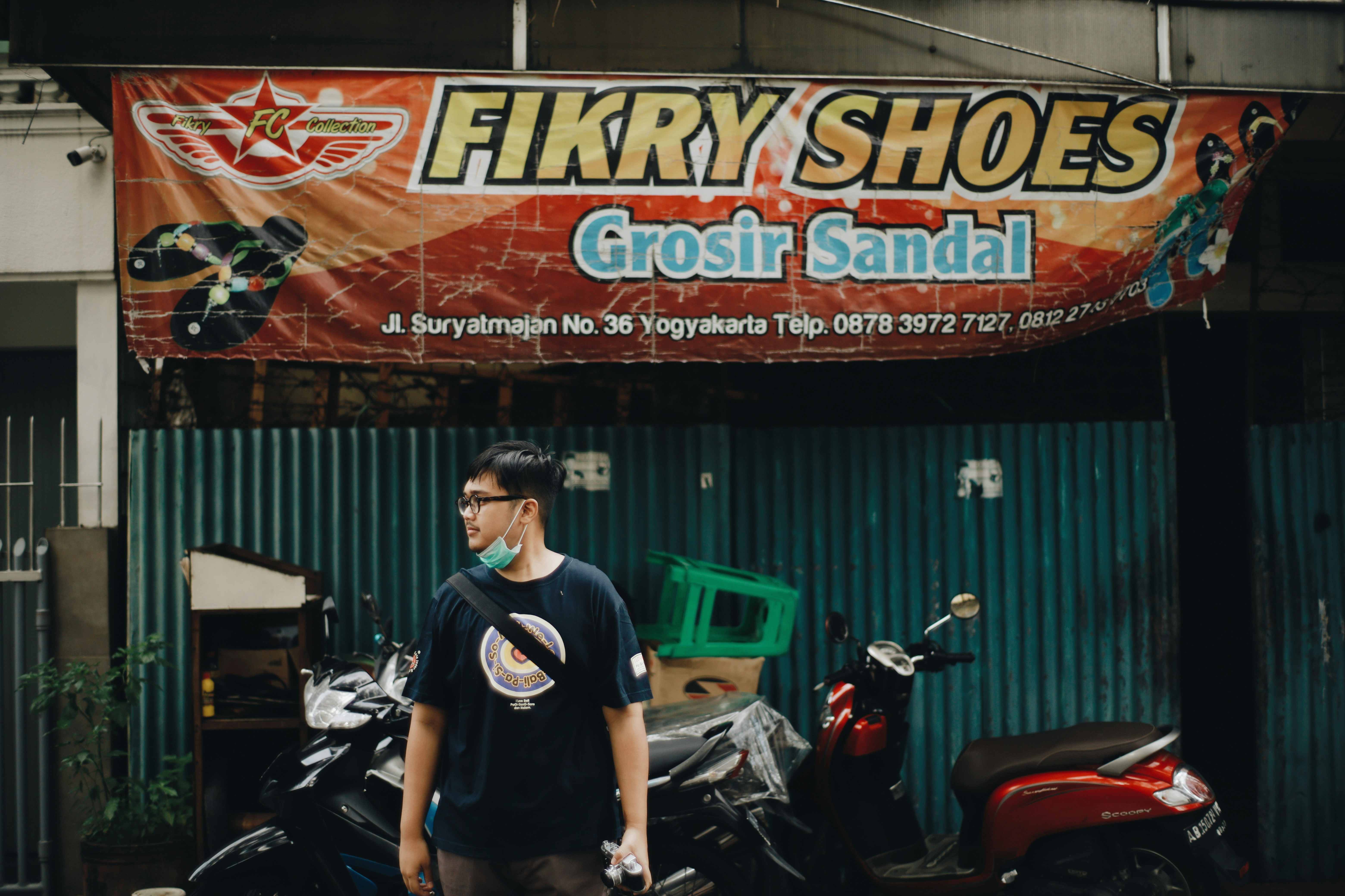 Pria berbaju kulit hitam crew neck T-shirt berdiri di samping sepeda motor