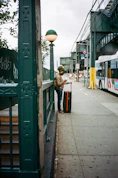 woman in brown coat standing beside green wooden signage