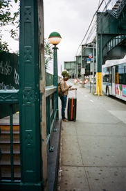 woman in brown coat standing beside green wooden signage