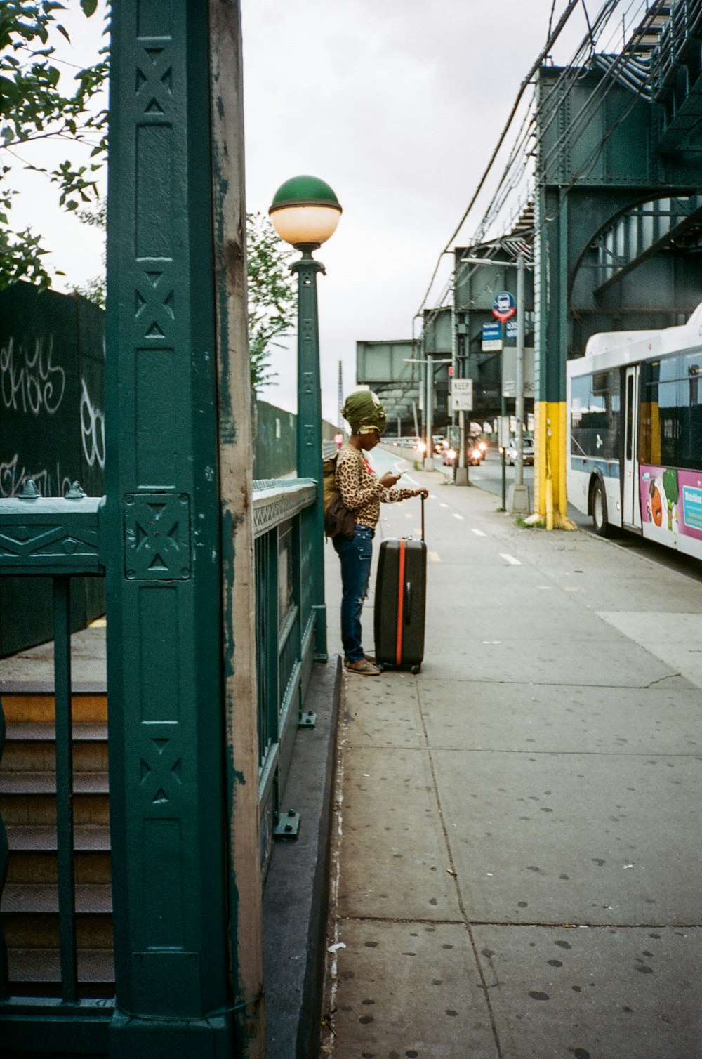 woman in brown coat standing beside green wooden signage