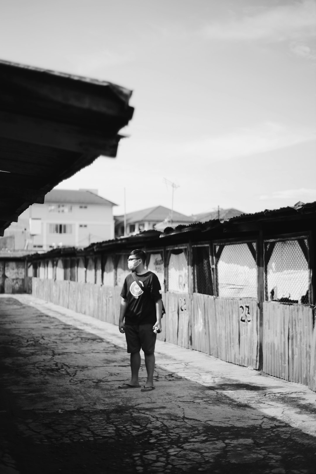 grayscale photo of woman walking on wooden bridge