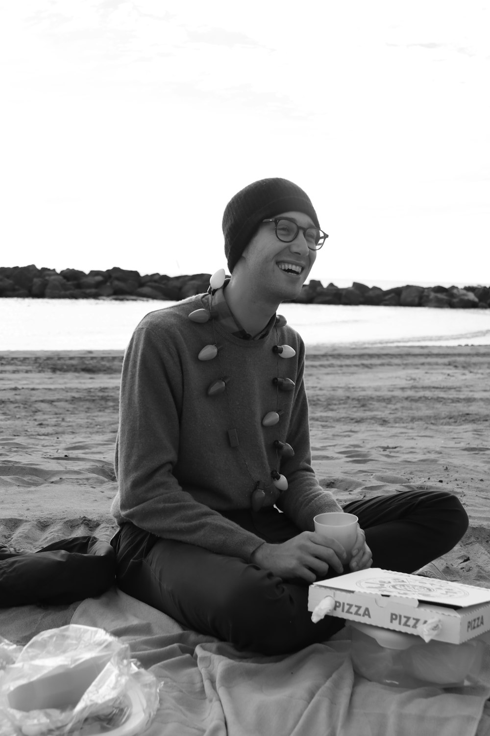 man in gray sweater sitting on wooden bench near body of water during daytime