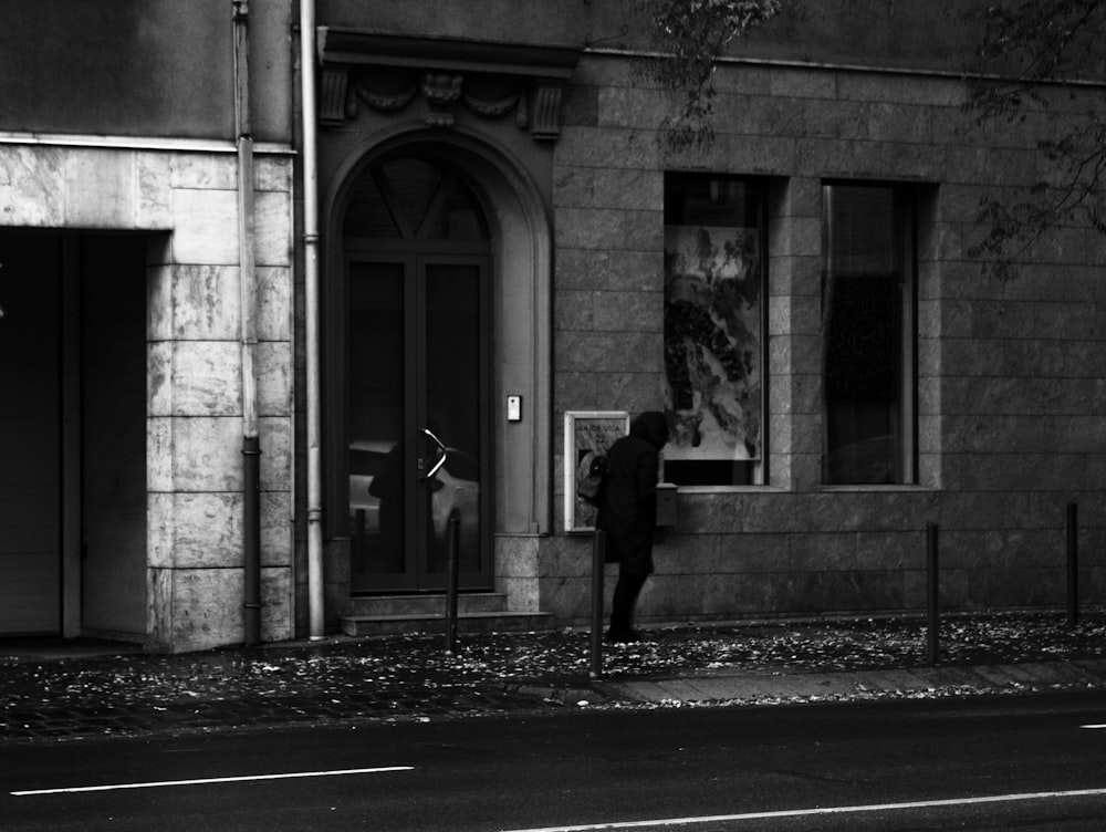 grayscale photo of man and woman walking on sidewalk