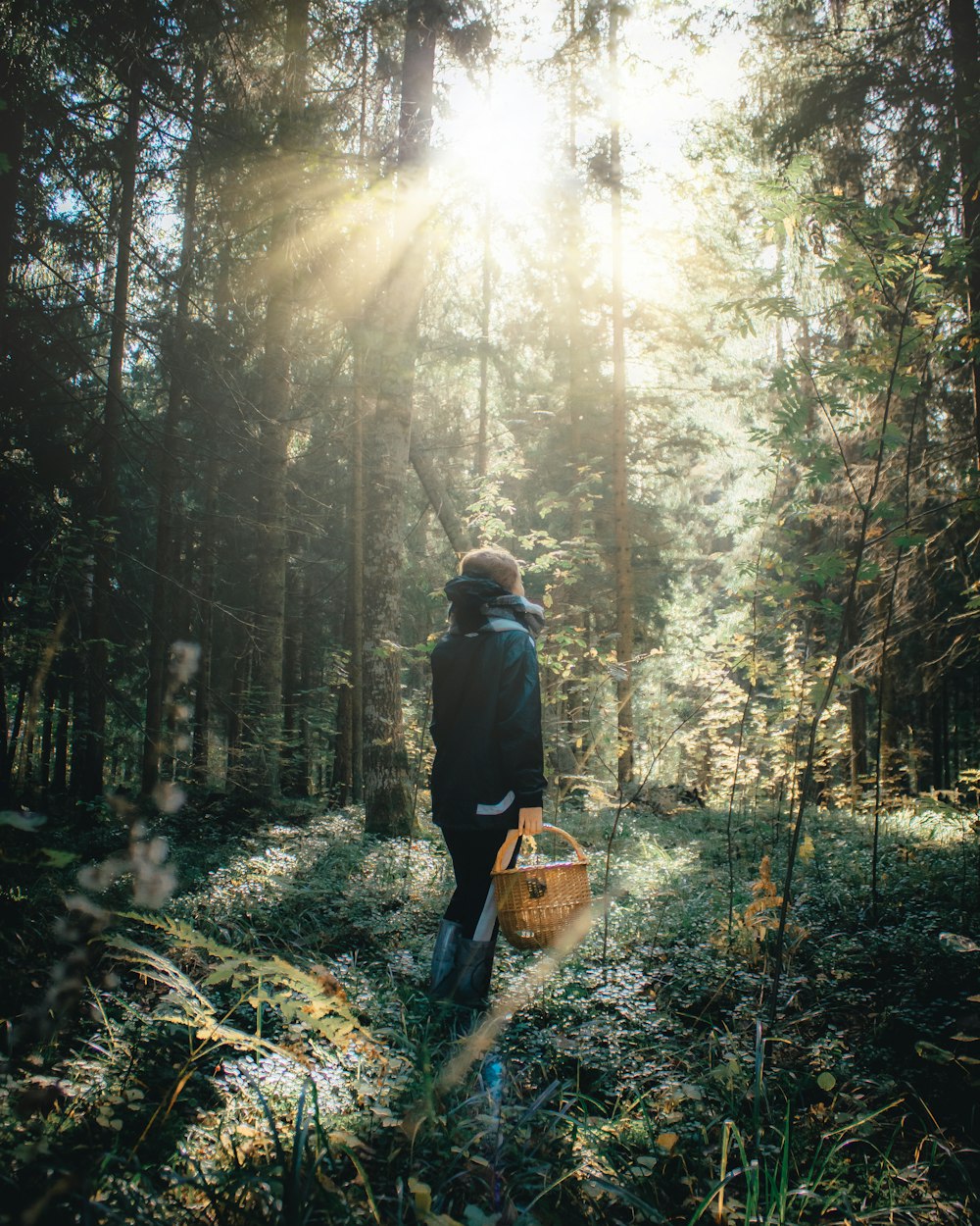 man in black jacket and brown backpack standing on forest during daytime