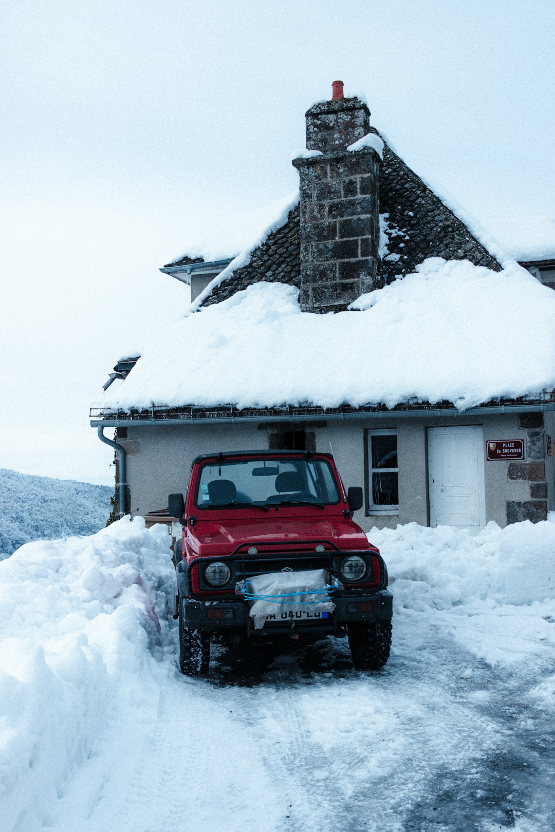 red jeep wrangler on snow covered ground near white wooden house during daytime