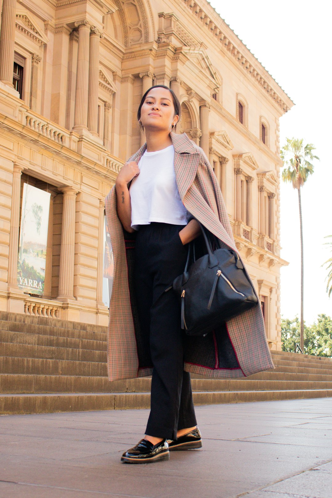 woman in black pants and white tank top standing on brown concrete stairs