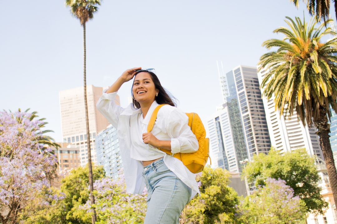 woman in white long sleeve shirt and blue denim jeans sitting on brown wooden seat during,