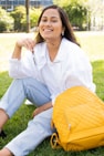 woman in white dress shirt and blue denim jeans sitting on green grass field during daytime