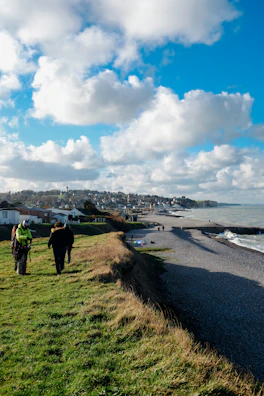 A scenic coastal path with travelers walking along the cliffs under a bright sky.