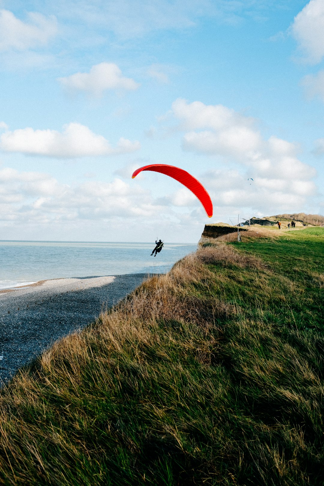 person in black shirt with red parachute over the sea during daytime