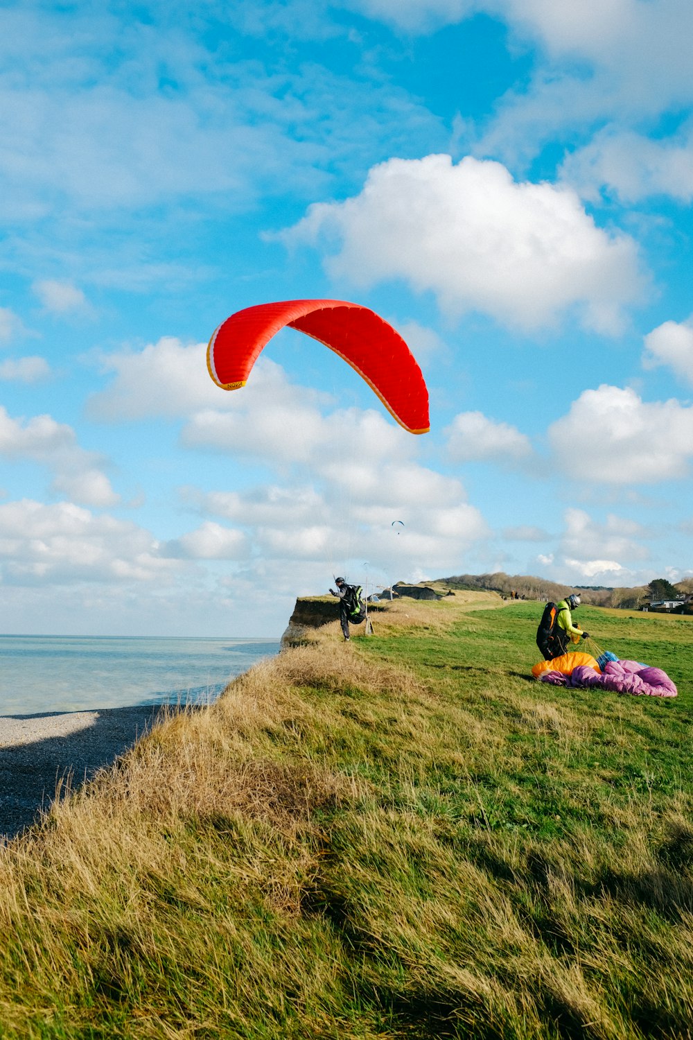 man and woman sitting on green grass field near body of water during daytime