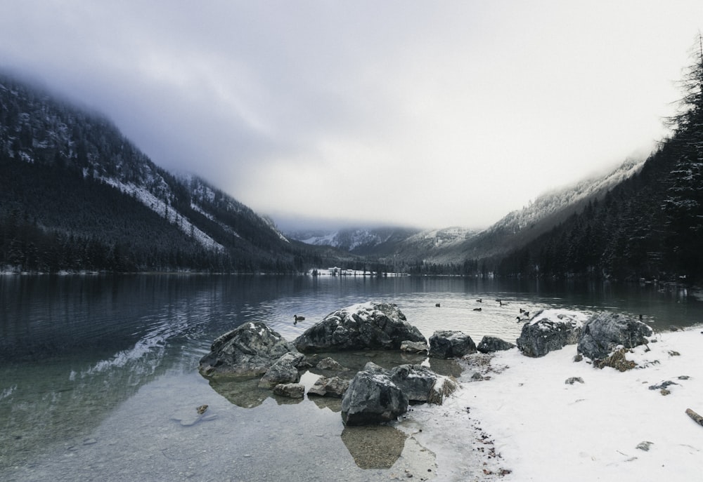 rochas cinzentas no lago perto da montanha durante o dia