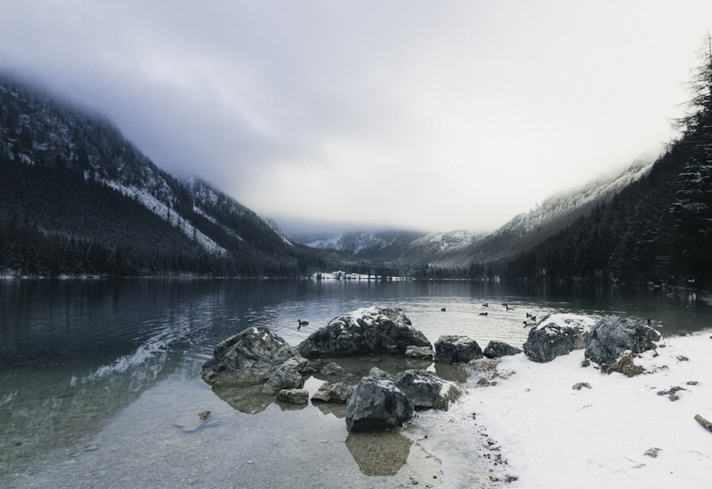 gray rocks on lake near mountain during daytime