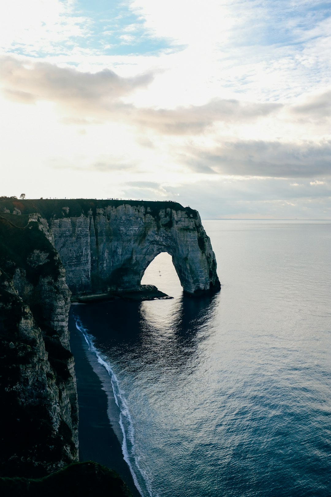 gray rock formation on sea under white clouds during daytime