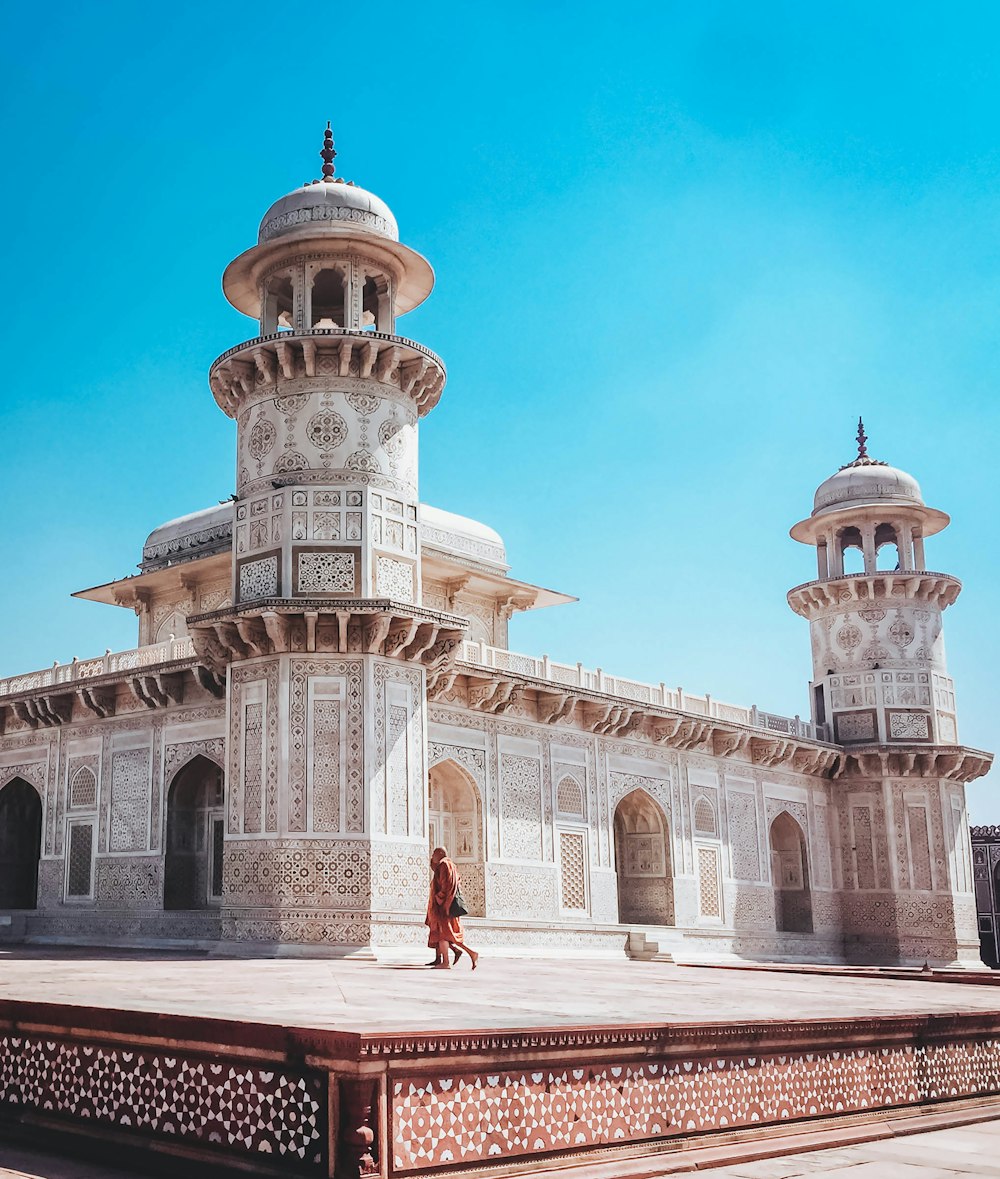 woman in red dress standing in front of white concrete building during daytime