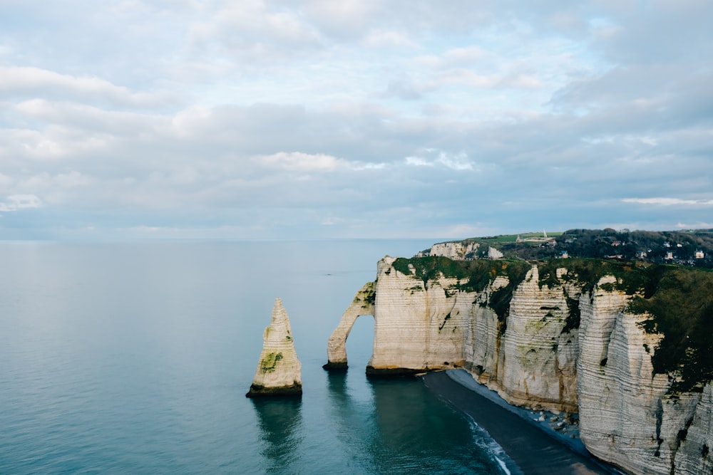 brown and green rock formation on body of water during daytime