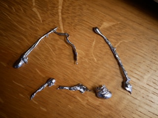 Close-up of shiny metal powders and solid metal pieces arranged neatly on a rustic wooden table.