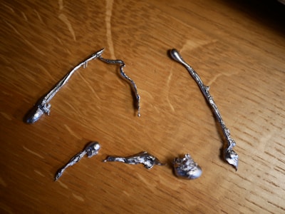 A close-up of various scrap metals arranged on a wooden surface.